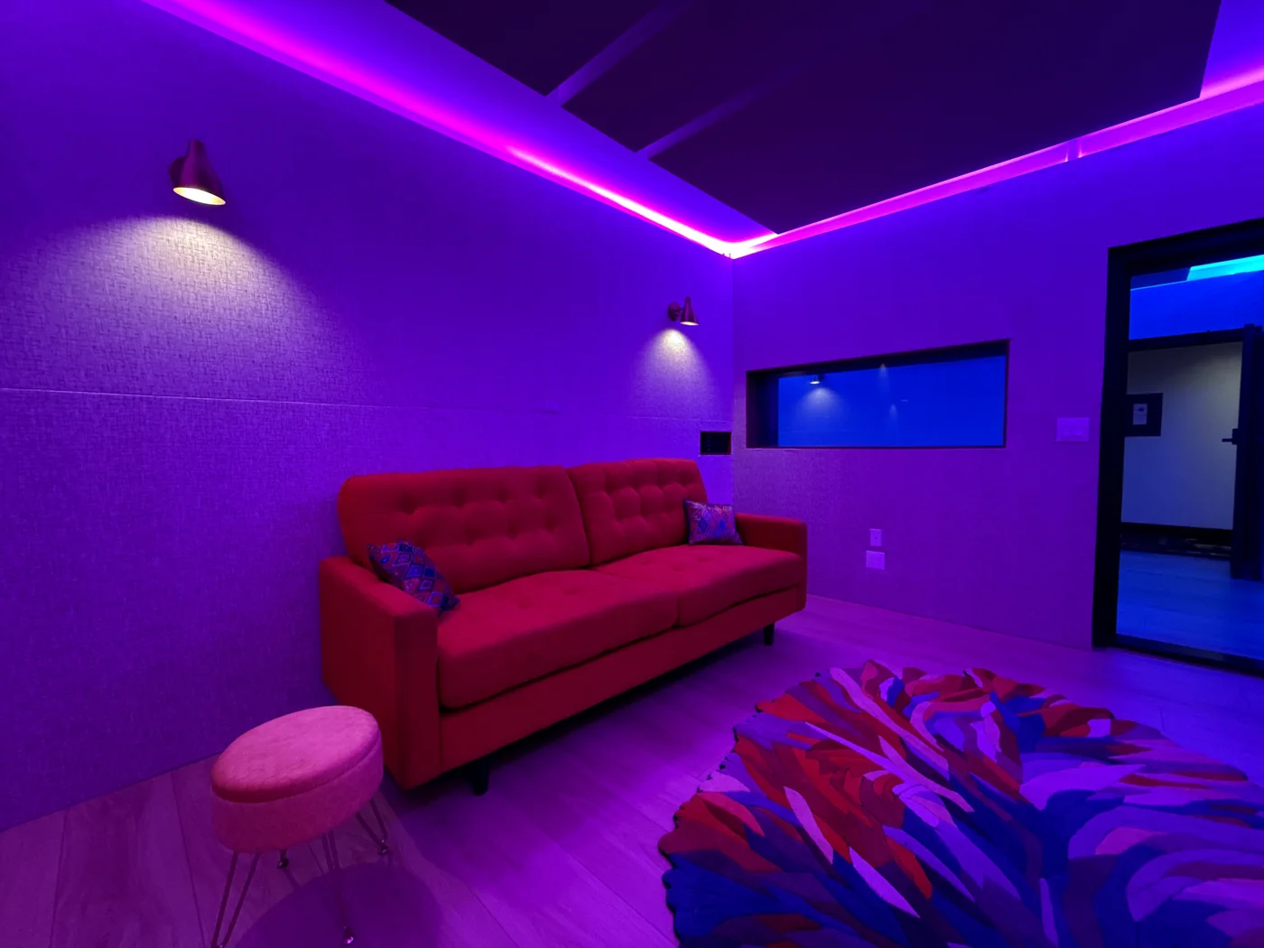A DTLA studio with violet lighting and red seating