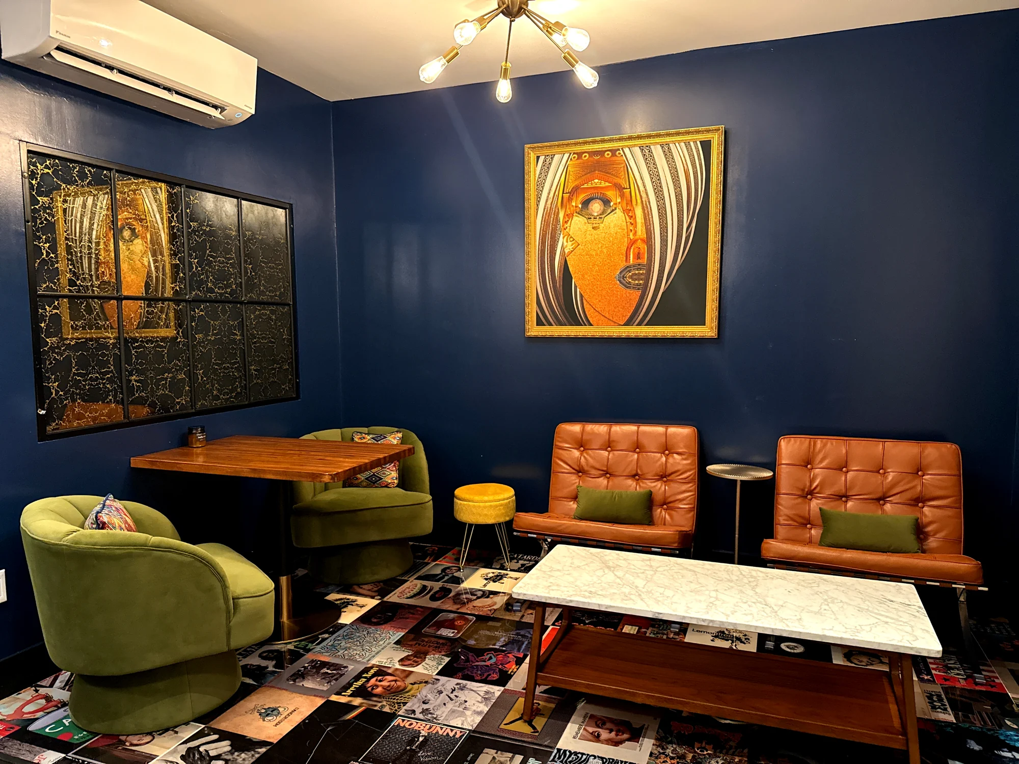 The DTLA lounge, with deep blue walls, a gold-framed portrait, leather chairs and green seating