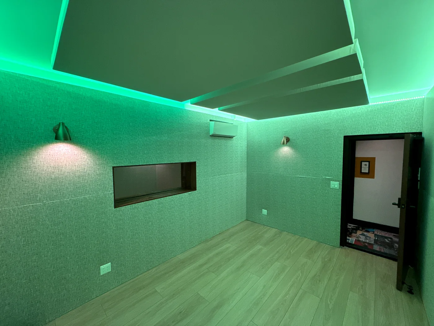 A DTLA studio with green cove lighting, acoustic ceiling clouds and an interior window
